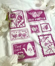 some white flowers and purple stamps on a bed sheet with the words stay positive, take it easy