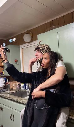 a man and woman in the kitchen taking a selfie with their cell phone camera