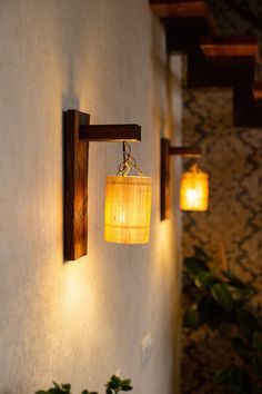 two lights are hanging from the side of a wall next to a potted plant