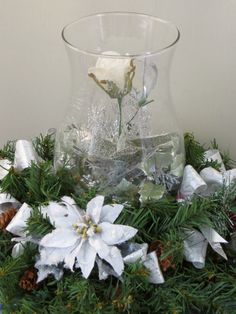 a glass vase filled with white flowers and greenery