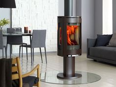 a wood burning stove in the middle of a room with chairs and tables around it