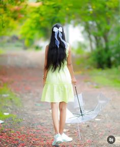 a woman walking down a road with an umbrella in her hand and the back of her head