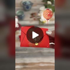 a person holding an envelope with a red paper on it and a chinese lantern hanging from the ceiling