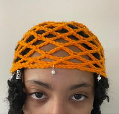 a close up of a person wearing an orange and black knitted headband with beads