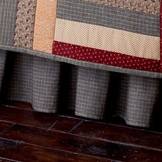 a cat is sitting on the edge of a window sill with a patchwork quilt behind it