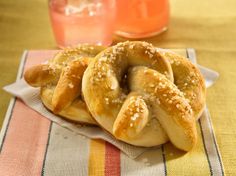 two soft pretzels sitting on top of a napkin next to a glass of orange juice