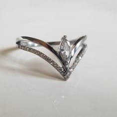 a white gold ring with diamonds on the sides and an arrow shaped design in the middle