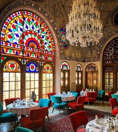 an ornate dining room with colorful stained glass windows and chandelier hanging from the ceiling