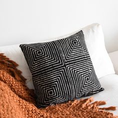 a black and white pillow sitting on top of a couch next to a brown blanket