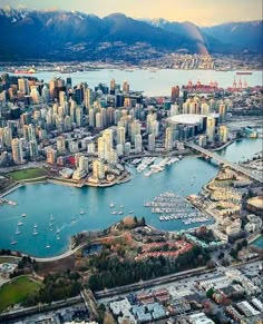 an aerial view of a city with boats in the water and mountains in the background