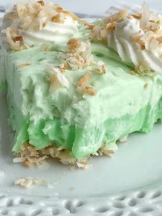 a piece of cake with green frosting and nuts on top sitting on a white plate