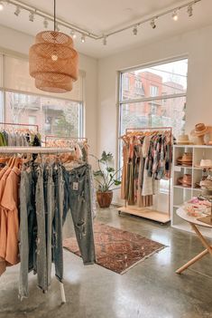 clothes hanging on racks in a clothing store with large windows and floor to ceiling windows