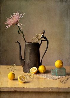 a still life with lemons, an onion and a flower in a watering can