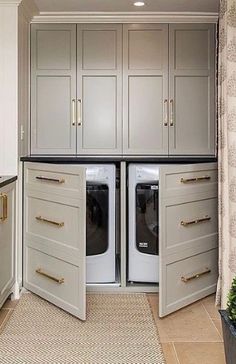 a washer and dryer are in the middle of a kitchen with white cabinets