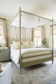 a bedroom with four poster bed and white curtains