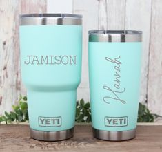 two personalized yeti tumblers sitting next to each other on a wooden table