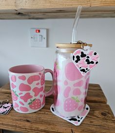 two mugs with strawberries on them are sitting on a table next to each other