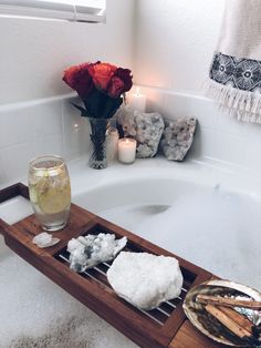 a bathtub with candles, soap and flowers in the tub next to it is filled with water