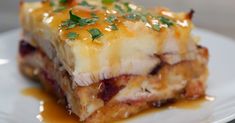 a white plate topped with lasagna covered in sauce and garnished with parsley