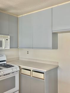 an empty kitchen with white appliances and gray cabinets