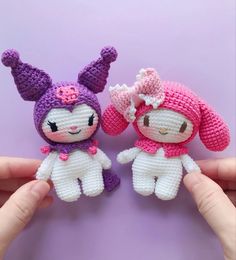 two small crocheted stuffed animals sitting next to each other on a purple surface