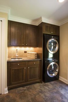 a washer and dryer are in the corner of this kitchen with dark wood cabinets