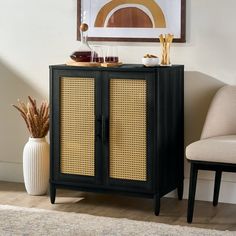 a black cabinet with wicker doors in the corner next to a chair and vase