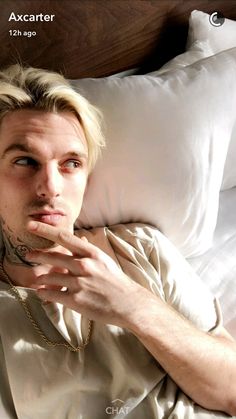 a man laying in bed with his hand under his chin