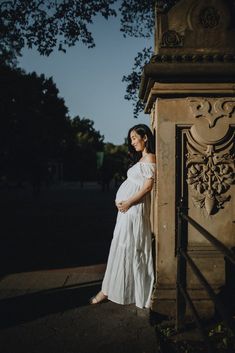 a pregnant woman standing in front of an ornate doorway with her hands on her belly