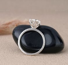 a diamond ring sitting on top of a black rock