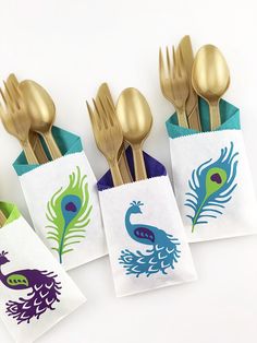 four napkins with peacock designs on them and gold forks in the middle are sitting next to each other