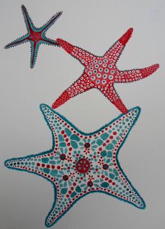 two red and blue starfishs are hanging from the ceiling in front of a white wall