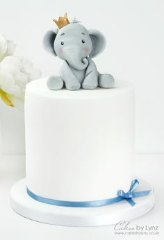 an elephant figurine sitting on top of a white cake with blue ribbon around it