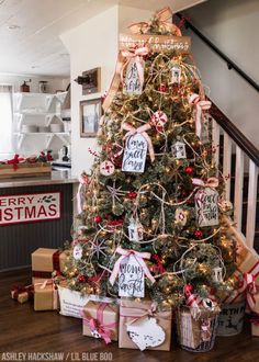 a christmas tree with presents under it and merry christmas tags on the top of it