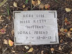 there is a plaque on the ground that says, here lies miss kittyy mittens'loyal friend