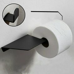 a roll of toilet paper is hanging on the wall next to a black towel rack