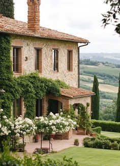 a large house with white flowers in front of it and trees around the outside area