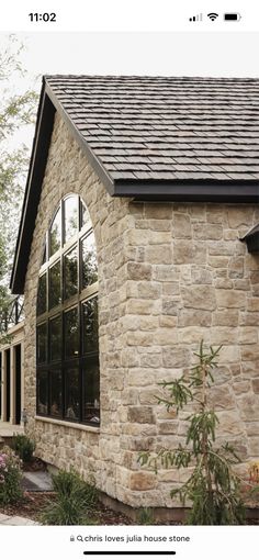 a stone house with black shingles and windows