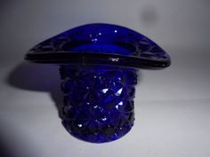 a blue glass vase sitting on top of a white table next to a black object