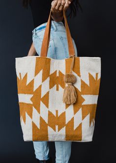 A girl can never have too many totes - especially when they're this cute! Our newest Aztec inspired tote is a must have for running errands or your next weekend getaway. Cream and camel Aztec inspired tote Camel pom tassel detail Leather suede straps Measures 16" x 6" x 16" Designed in the U.S.A. Produced in India.  100% Cotton Lining: 100% Polyester White Bohemian Bag With Double Handle, Bohemian White Bags With Double Handle, Cream Bohemian Bags With Leather Handles, Bohemian Cream Bags With Leather Handles, Bohemian White Bags With Handles, White Bohemian Canvas Bag For Daily Use, White Bohemian Canvas Bag, White Bohemian Bag With Removable Pouch, Bohemian White Bag With Removable Pouch