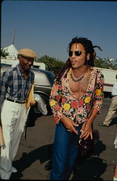 a man with dreadlocks standing next to another man wearing sunglasses and a floral shirt