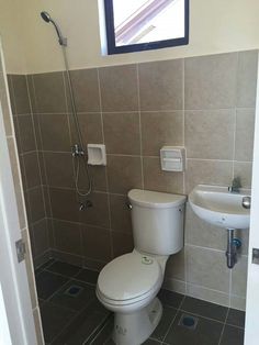 a white toilet sitting in a bathroom next to a sink and shower faucet