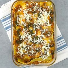 a casserole dish with meat, cheese and spinach is on a towel