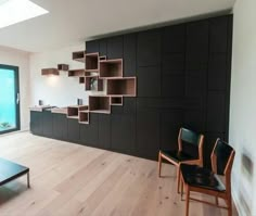 a living room filled with furniture next to a large glass window covered in light brown bookshelves