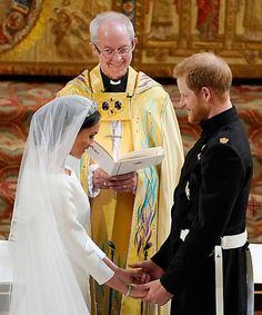 a man and woman standing next to each other in front of a priest holding a book