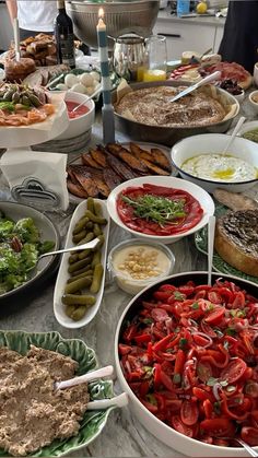 a table filled with lots of different types of food on plates and serving utensils