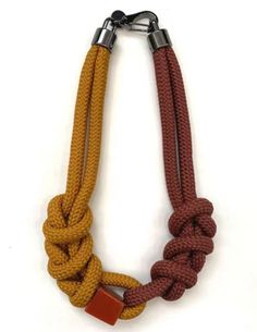 an orange and brown rope is attached to a metal caramel colored necklace with two silver clasps