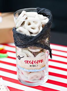 a jar filled with white and black candy on top of a red and white table