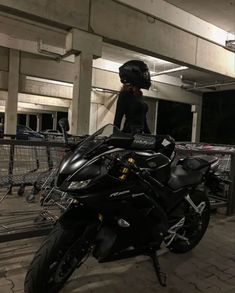 a woman standing on top of a black motorcycle