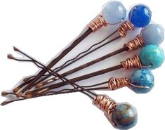 several different colored beads are attached to copper wire and hang on the ends of hair pins